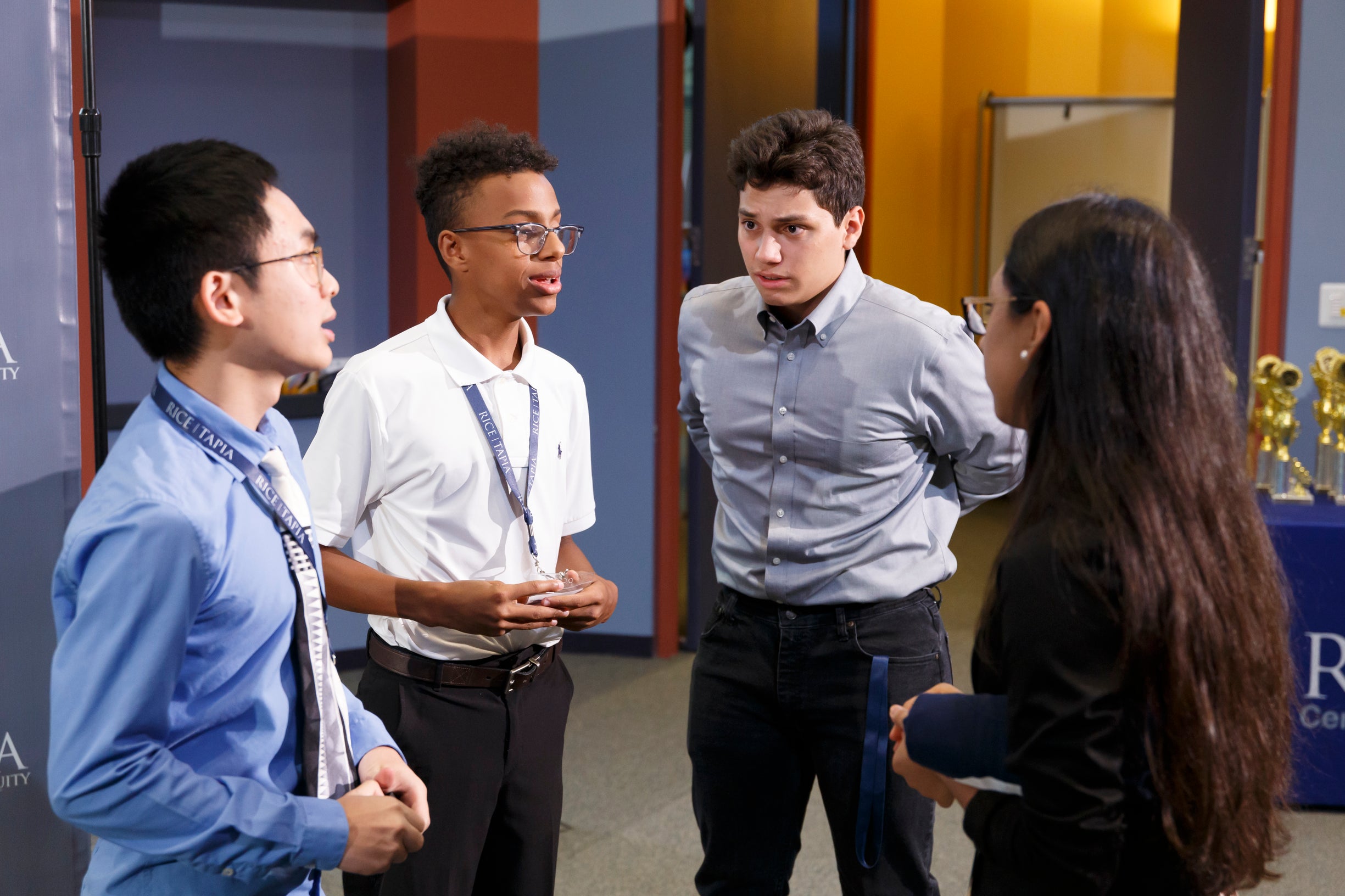 4 students preparing for presentation while standing in a group.